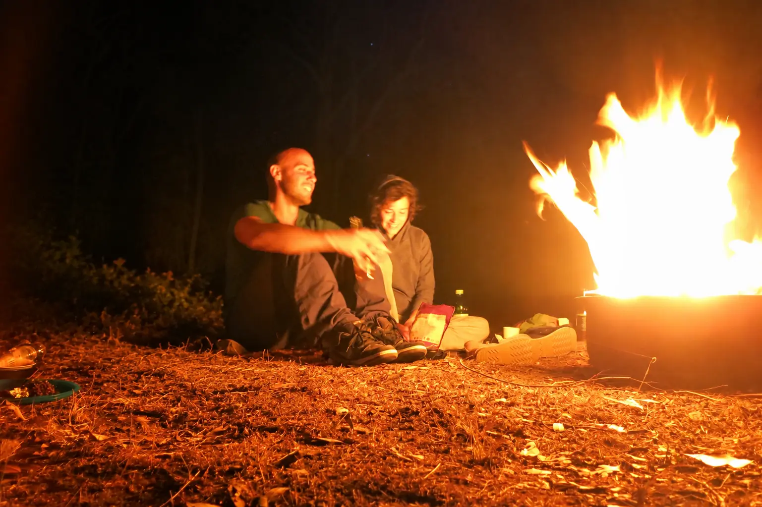 Camilo en zijn zus 's avonds bij een kampvuur in het bos.